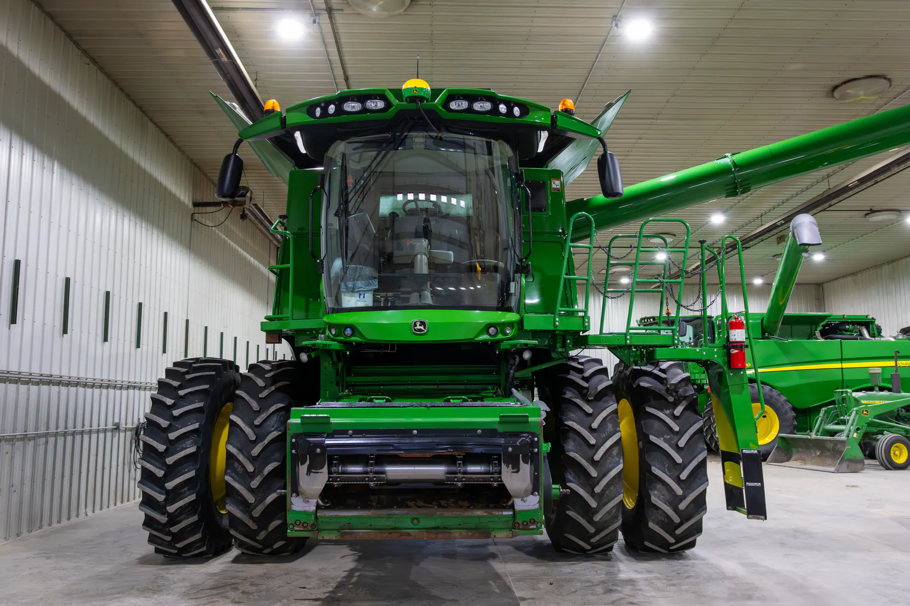 Clean green John Deere combine inside a large equipment shop
